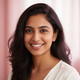 Close-up portrait of a smiling South Asian woman, exuding happiness and trust, against a softly blurred rose and blush pink b